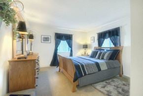 Rochester apartment for rent - Master bedroom with blue curtains and nightstand lamp at Chili Heights Apartments, New York, 14624