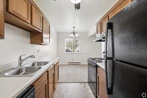 Rochester apartment for rent - A kitchen with a black refrigerator and wooden cabinets.