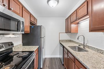 Williamsville townhouse for rent - A kitchen with a black stove top oven, a black refrigerator, and brown cabinets.