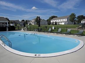 Farmington townhouse for rent - A large outdoor swimming pool with a white fence around it.