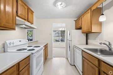 Fairport townhouse for rent - A kitchen with white appliances and wooden cabinets.
