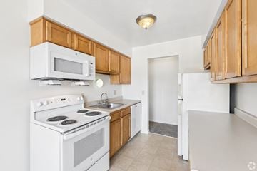 Rochester apartment for rent - A kitchen with white appliances and wooden cabinets.