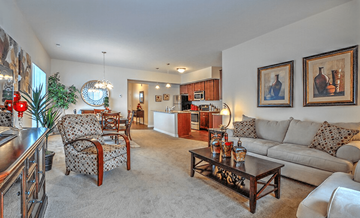 Lancaster townhouse for rent - A living room with a grey couch, a wooden coffee table, and a dining table with chairs.