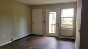 Friendship apartment for rent - an empty living room with two doors and a wood floor