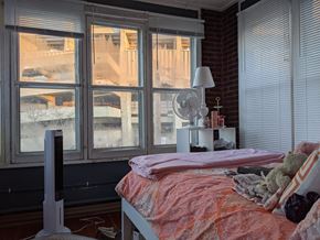 Madison apartment for rent - A bedroom with a bed, a fan, and a window with a view of a snowy landscape.