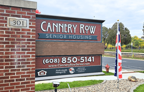Waunakee apartment for rent - A sign for Cannery Row Senior Housing is displayed in front of a brick wall.