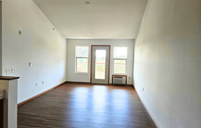 Waunakee apartment for rent - A room with a brown floor and a white wall with a window.