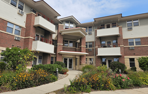 Waunakee apartment for rent - A multi-story apartment building with a landscaped courtyard in front.