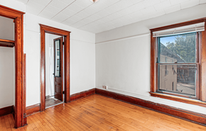 Madison apartment for rent - A room with a wooden floor and a window showing a building outside.