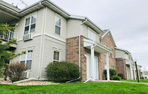 Baraboo apartment for rent - a white and brick apartment building with a green lawn in front of it