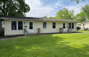 Leroy apartment for rent - A house with a white siding and a black door is surrounded by a green lawn.