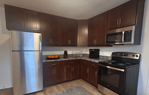 Madison apartment for rent - A kitchen with a stainless steel refrigerator, black oven, and wooden cabinets.