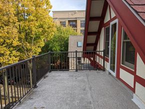 Madison apartment for rent - A balcony with a black railing and a red and white building in the background.