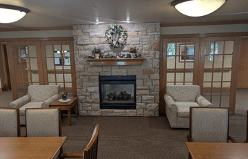 Greenfield apartment for rent - a living room with a stone fireplace and a table and chairs