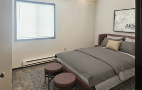 Marshall apartment for rent - A bedroom with a bed, two stools, and a window.