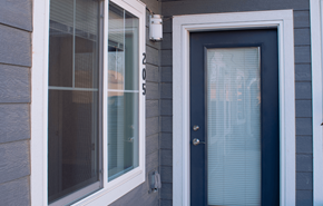 Darlington apartment for rent - A blue door is on the right side of a house with a window on the left.