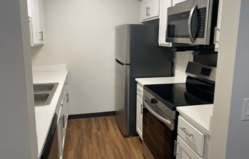 Beloit apartment for rent - A black refrigerator and microwave in a kitchen with white cabinets.