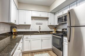 Newport News apartment for rent - A renovated kitchen with white cabinets, stainless steel appliances and a black granite countertop.