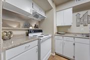 Temple apartment for rent - a kitchen with white appliances and granite counter tops and white cabinets at Parks on the Green, Temple, Texas