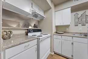 Temple apartment for rent - White kitchen with electric stove and overhead cabinets at Parks on the Green Apartments, Temple, TX 76504