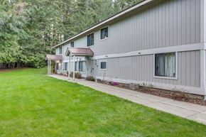 Priest River apartment for rent - a white house with a yard and a sidewalk
