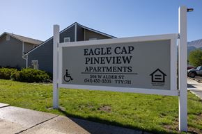 Joseph apartment for rent - A sign for Eagle Cap Pineview Apartments is displayed in front of some houses.
