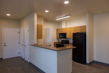 Pendleton apartment for rent - A kitchen area with a black refrigerator and white cabinets.
