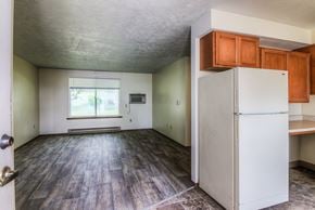Warden apartment for rent - A room with a white fridge and wooden floors.