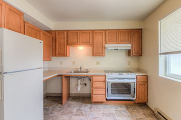 Warden apartment for rent - A kitchen with wooden cabinets and a white refrigerator.