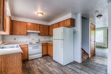 Warden apartment for rent - A kitchen with a white fridge and wooden cabinets.