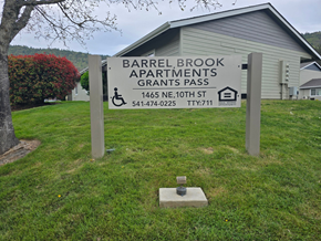 Grants Pass apartment for rent - A sign for Barrel Brook Apartments stands in front of a building.