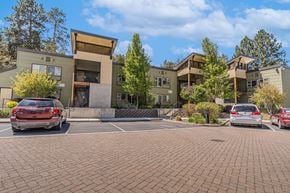 Bend apartment for rent - A parking lot with cars and apartment buildings in the background.
