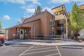 Bend apartment for rent - A brown building with a parking lot in front.