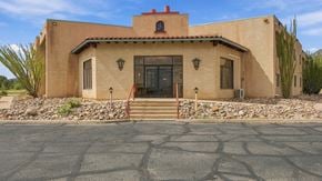Bisbee apartment for rent - A house with a red tile roof and a stone wall in front.