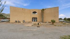 Bisbee apartment for rent - A tan building with a large arched doorway and a small window above it.