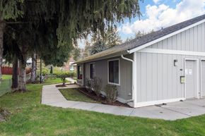 Newport apartment for rent - A small building with a grey roof and a white door is surrounded by a grassy area and trees.
