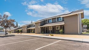 Grants Pass apartment for rent - a row of houses with a parking lot and a blue sky