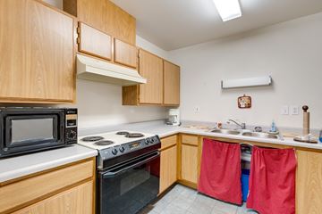Colville apartment for rent - a kitchen with wooden cabinets and a stove microwave and sink