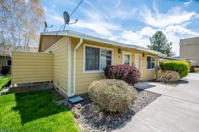 Wallowa apartment for rent - the front of a yellow house with a lawn and a driveway