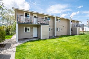 Enterprise apartment for rent - the front of a tan house with a yard and a balcony