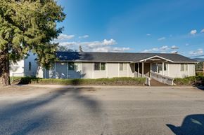 Newport apartment for rent - A house with a grey roof and white walls is surrounded by a driveway and a tree.