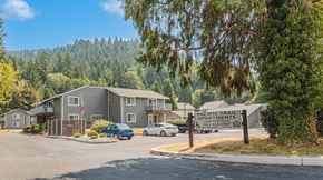Canyonville apartment for rent - a building with a sign in front of it and trees