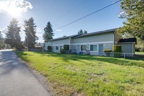 Spirit Lake townhouse for rent - A house with a white exterior and a grey roof is surrounded by a grassy lawn and trees.