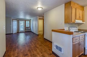 Sandy apartment for rent - an empty kitchen and living room with wood flooring