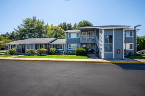 The Dalles apartment for rent - A large grey building with a red fire hydrant in front.