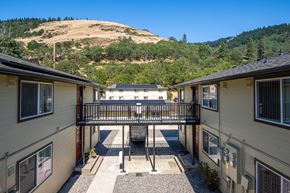 White Salmon apartment for rent - A view of a courtyard between two houses with a hill in the background.