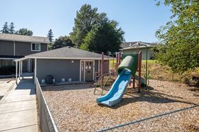 Cascade Locks apartment for rent - A playground with a green slide and a grey building in the background.