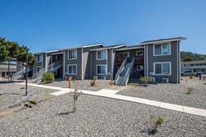 Gold Beach apartment for rent - A row of modern townhouses with gravel driveways in front.