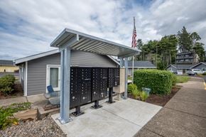 Lincoln City apartment for rent - A grey building with a flag on top and a row of mailboxes in front.