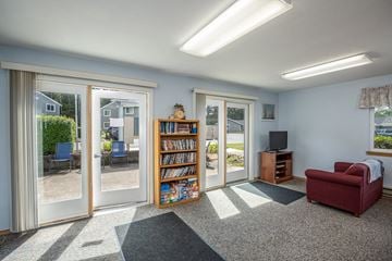 Lincoln City apartment for rent - A living room with a red chair and a bookshelf filled with books.
